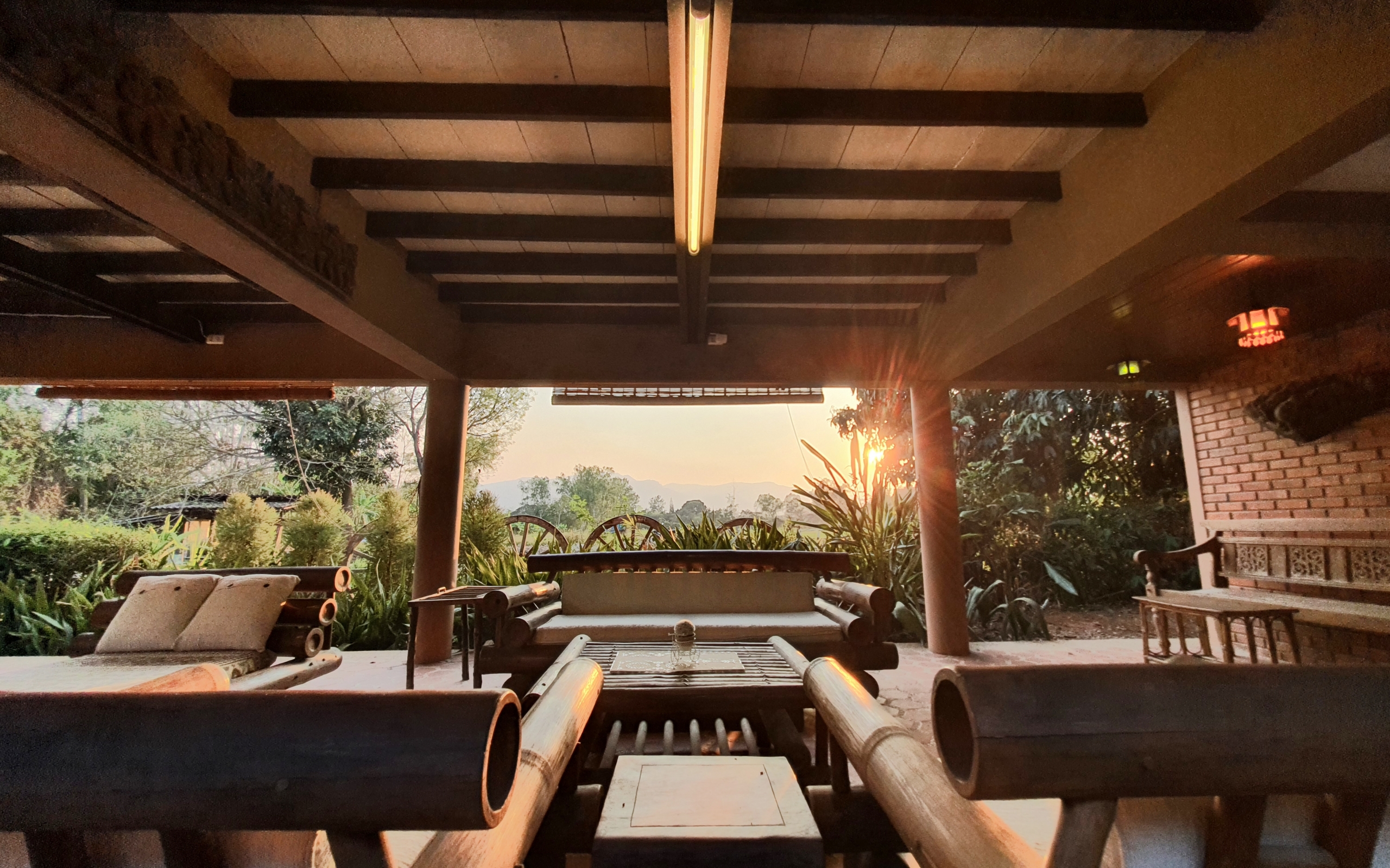 A wooden covered patio at sunset, with the sun casting a warm glow over the area