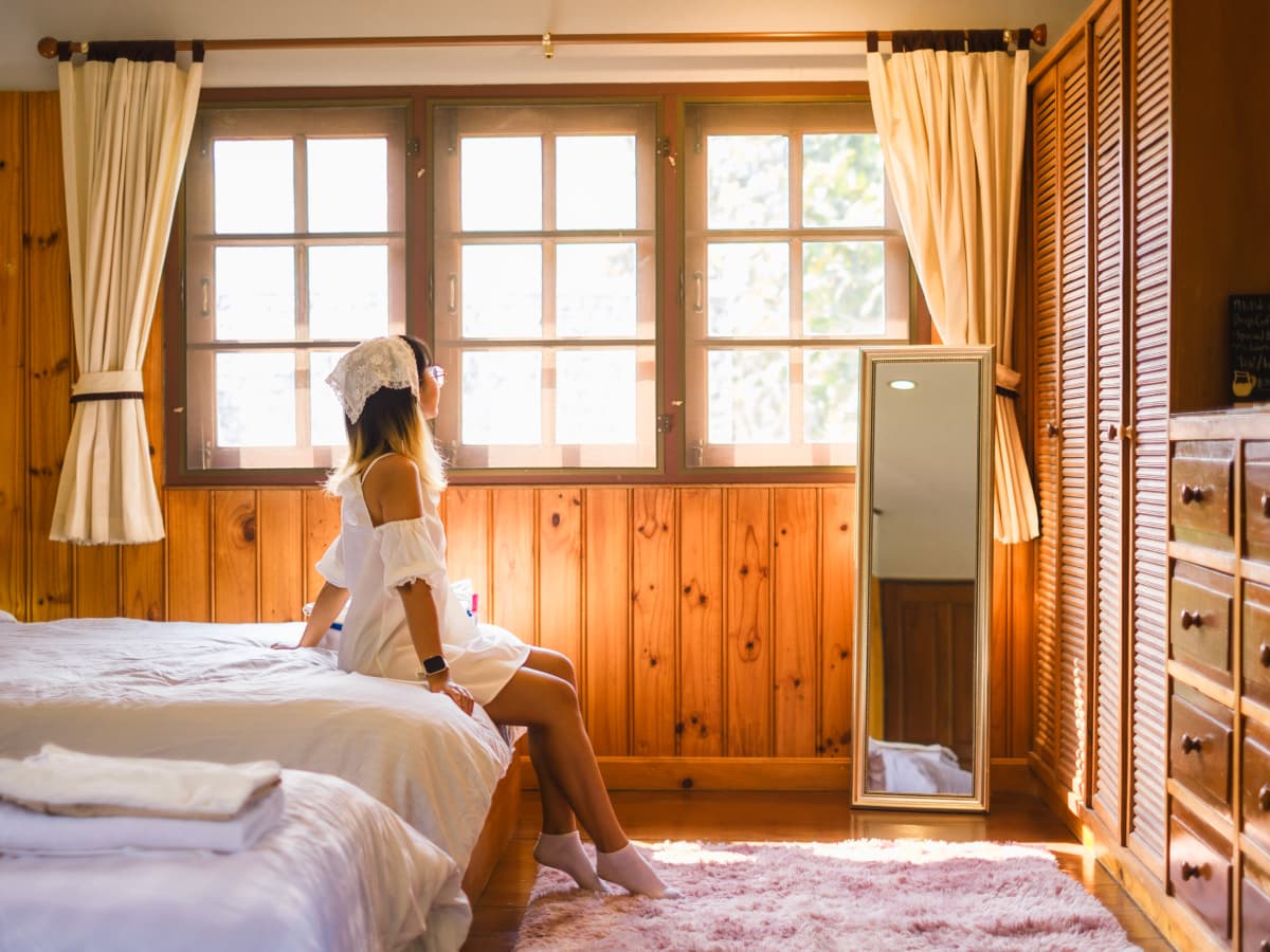 A woman sitting on bed, looking out the window