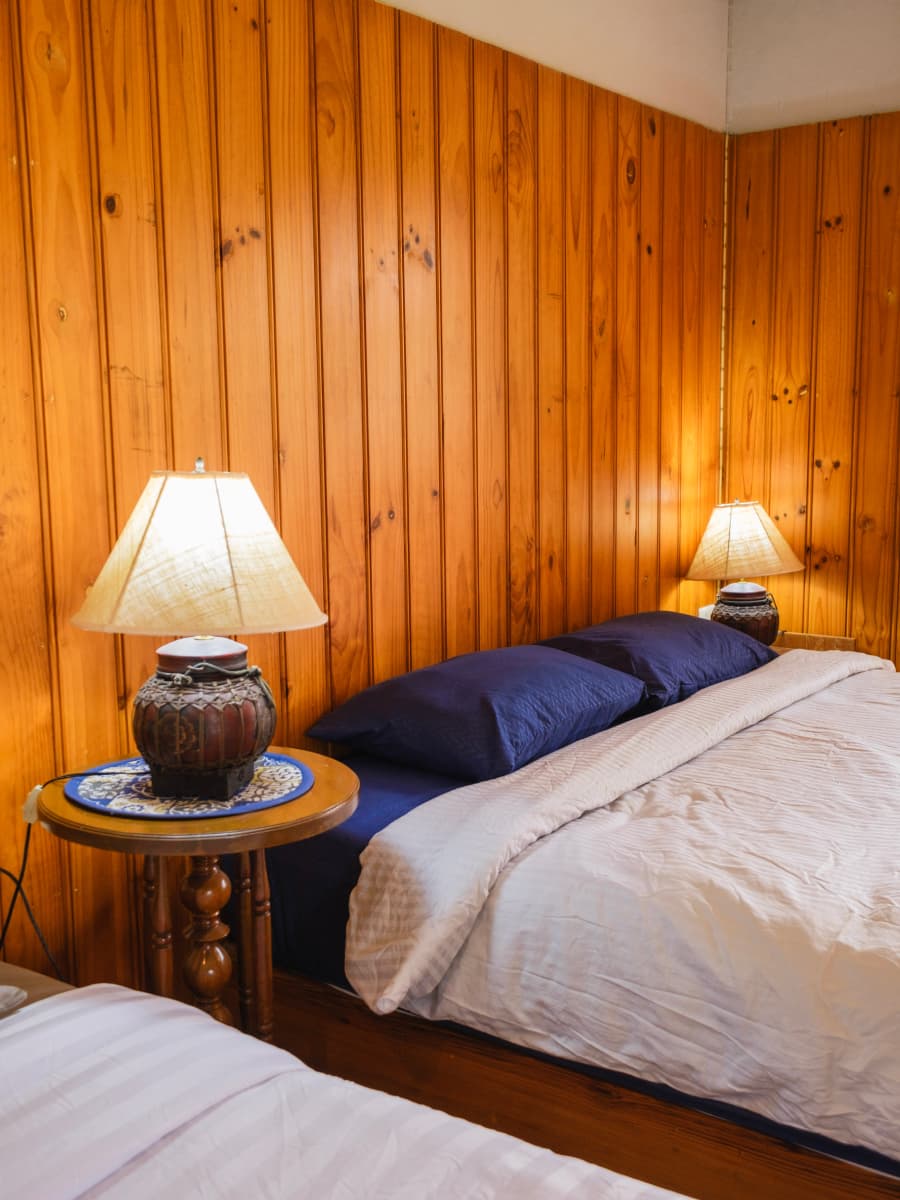 Interior with bed and lamps against wood paneling