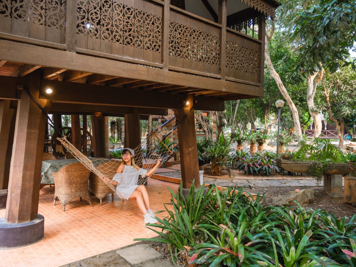 A woman relaxing on a hammock in front of a house